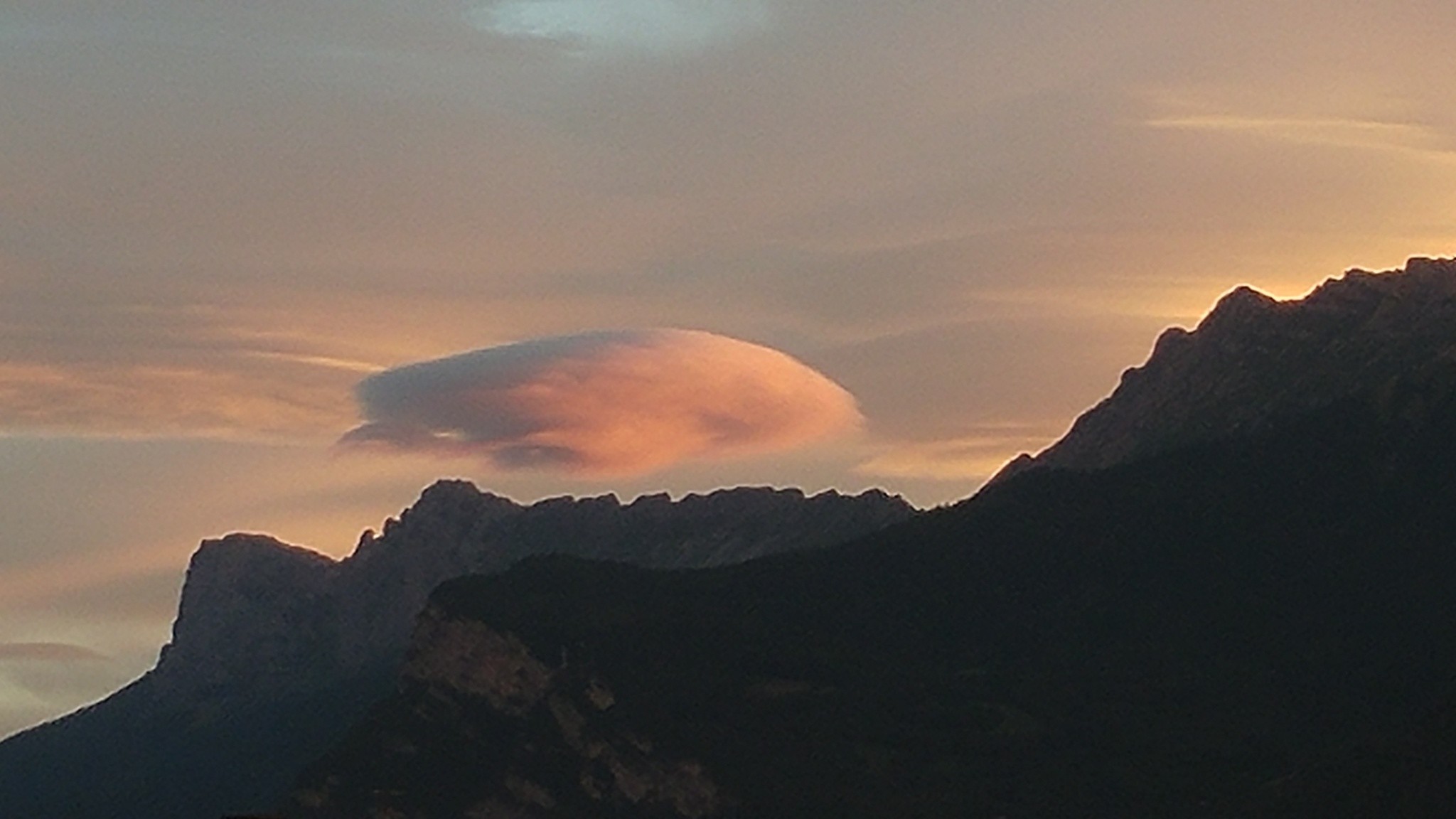 Un drôle de nuage façon béret, éclairé en orange par la droite, au-dessus du profil du Vercors. 